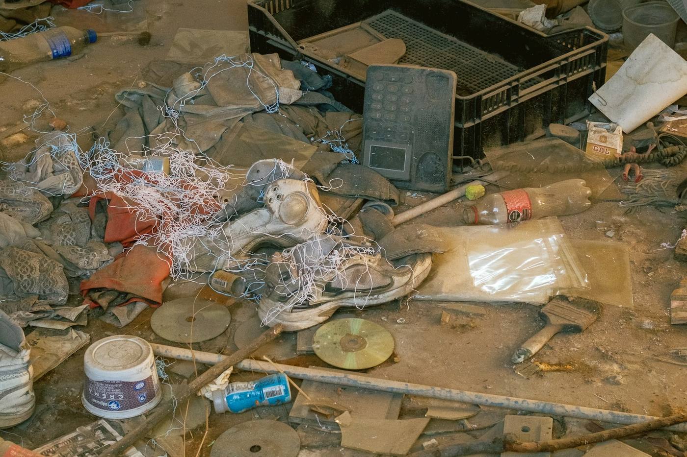 A floor covered in broken tile, debris and discarded items